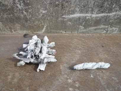 新聞紙1枚を半分に折り、それをまた縦長に半分に折り丸めて、ギュッとひねります。